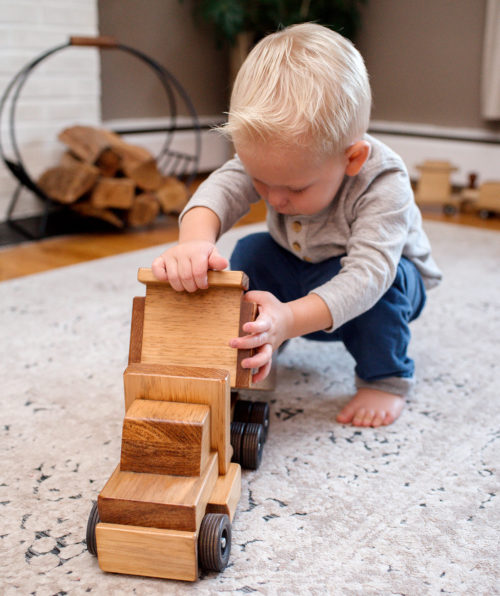 boy playing with wooden dump truck